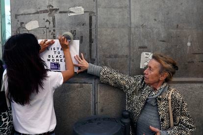 Dos mujeres pegan un cartel durante la manifestación celebrada en Málaga.