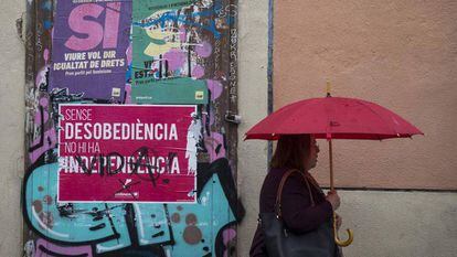 Una mujer pasa ante un cartel del publicidad del referéndum del 1 de octubre en una calle de Barcelona.