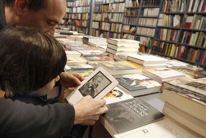 Dos lectores consultan un libro digital en una librería tradicional.