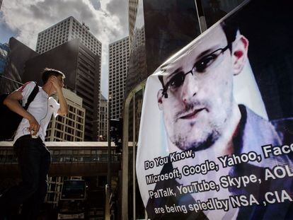 Un joven en Hong Kong pasa delante de un cartel de Edward Snowden, denunciante de espionaje por parte de la Agencia de Seguridad Nacional estadounidenses de empresas tecnológicas.