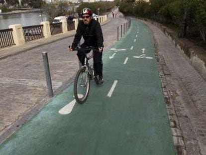 Un hombre pedalea frente a la Torre del Oro por el carril bici de Sevilla.