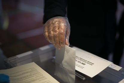 Un hombre deposita su voto con un guante protector en el colegio electoral de los Maristas en el paseo Sant Joan, en Barcelona.