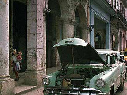 Dos cubanos reparan su coche en una calle de La Habana Vieja.