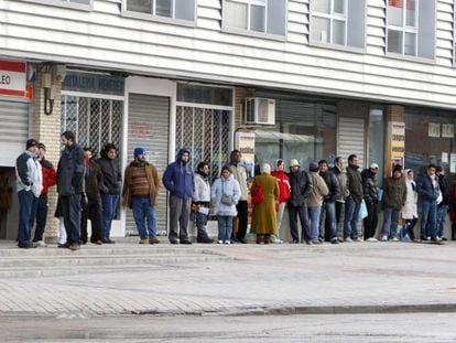 Varias personas forman una larga cola ante una oficina de empleo