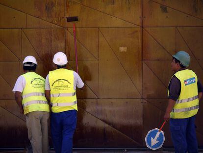 Varios obreros de la construcción pintan una chapa en una obra en el centro de Madrid.