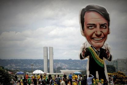 Seguidores del presidente electo, Jair Bolsonaro, caminan frente a un muñeco gigante con su figura en la Explanada de los Ministerios.
