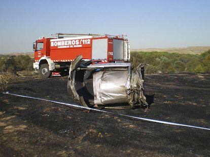 Delante del camión de bomberos, los restos de la turbina derecha del MD-82 con uno de los  sistemas de freno del avión, la reversa (la parte metálica que sobresale a la izquierda del motor), desplegada.