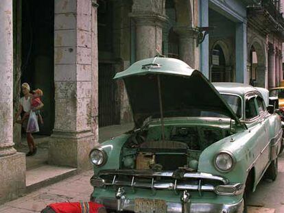 Dos cubanos reparan su coche en una calle de La Habana en 1999.