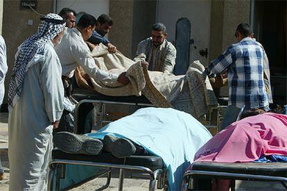 Un grupo de iraquíes identifica los cadáveres de varios fallecidos en los atentados de ayer en Bagdad.