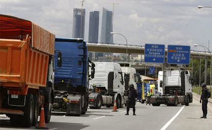 Dos agentes antidisturbios controlan los camiones que bloqueban el acceso a Madrid por la autopista A-1 de Burgos.