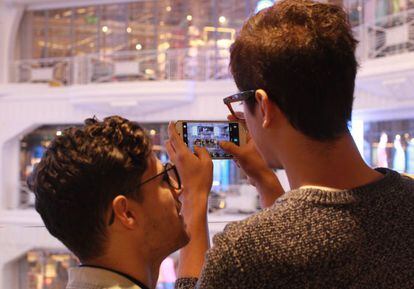 Dos usuarios hacen una foto con su m&oacute;vil en un centro comercial de Madrid.