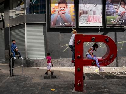 Un grupo de niños juega en la P de un cartel de PDVSA en las calles de Caracas el 2 de enero.