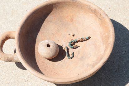 Los arqueólogos encontraron juntos este inusual plato de cerámica de un solo asa y dos anzuelos.