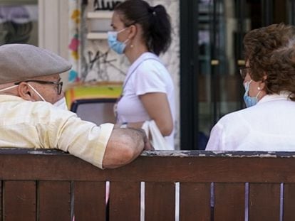 Una pareja de ancianos con mascarilla sentada en un banco en Madrid.