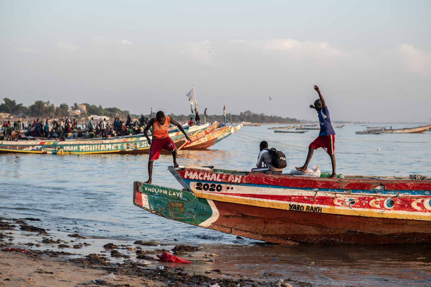 Muchachos merodeando por las embarcaciones que los migrantes utilizan para salir hacia Canarias desde Mbour, en Senegal. / SYLVAIN CHERKAOUI