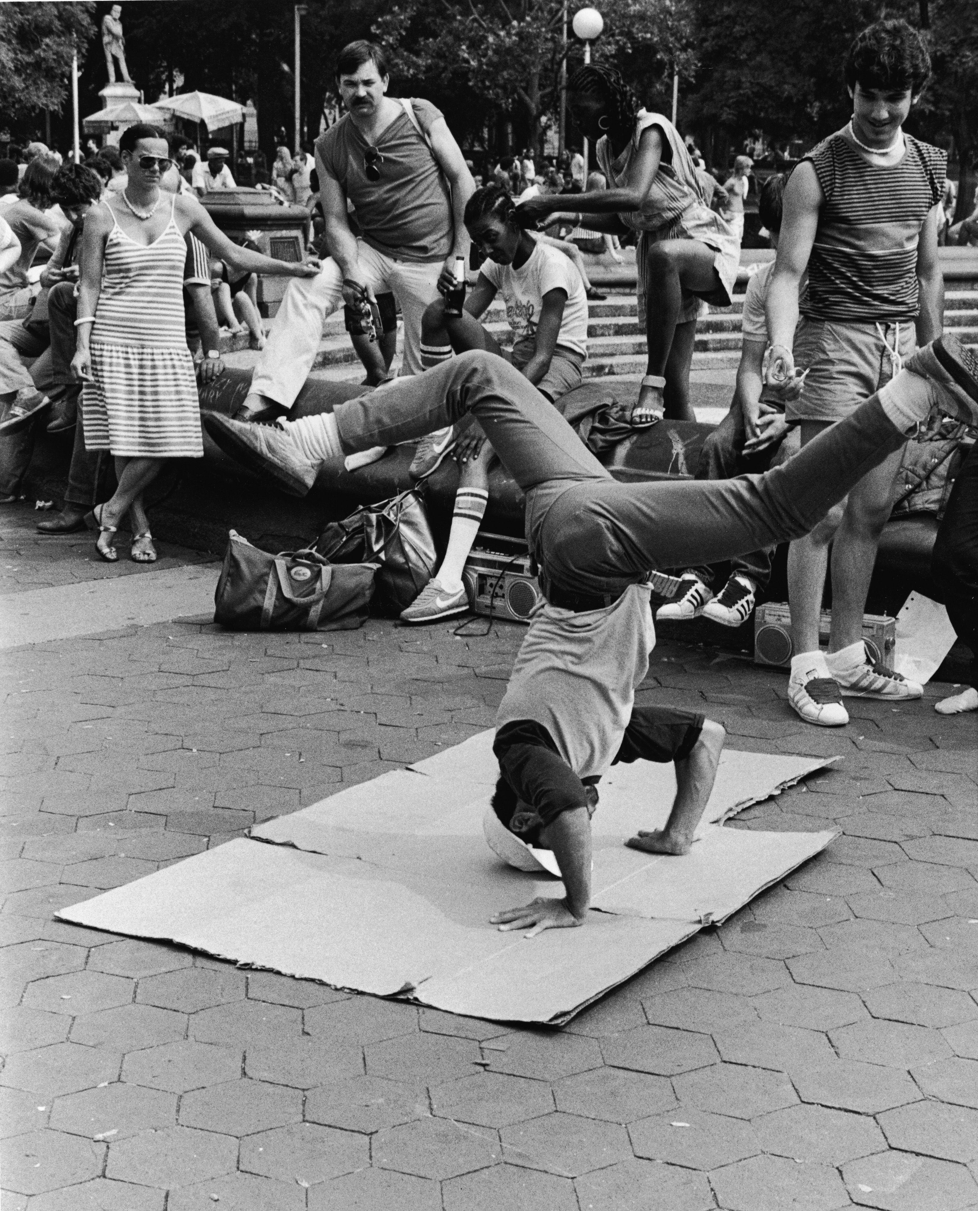Un joven baila 'breakdance' observado por un grupo de espectadores, en el parque Washington Square de Nueva York a principios de la década de los ochenta.