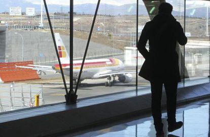 Un pasajero observa un avi&oacute;n de Iberia en el aeropuerto de Barajas.