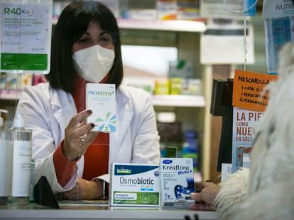 Una farmacéutica dispensa probióticos a un cliente en una botica de Madrid.