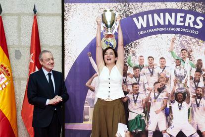 La presidenta de la Comunidad de Madrid, Isabel Díaz Ayuso, levanta la miniréplica de la Copa de Europa que le acaba de entregar el presidente del Real Madrid, Florentino Pérez. 