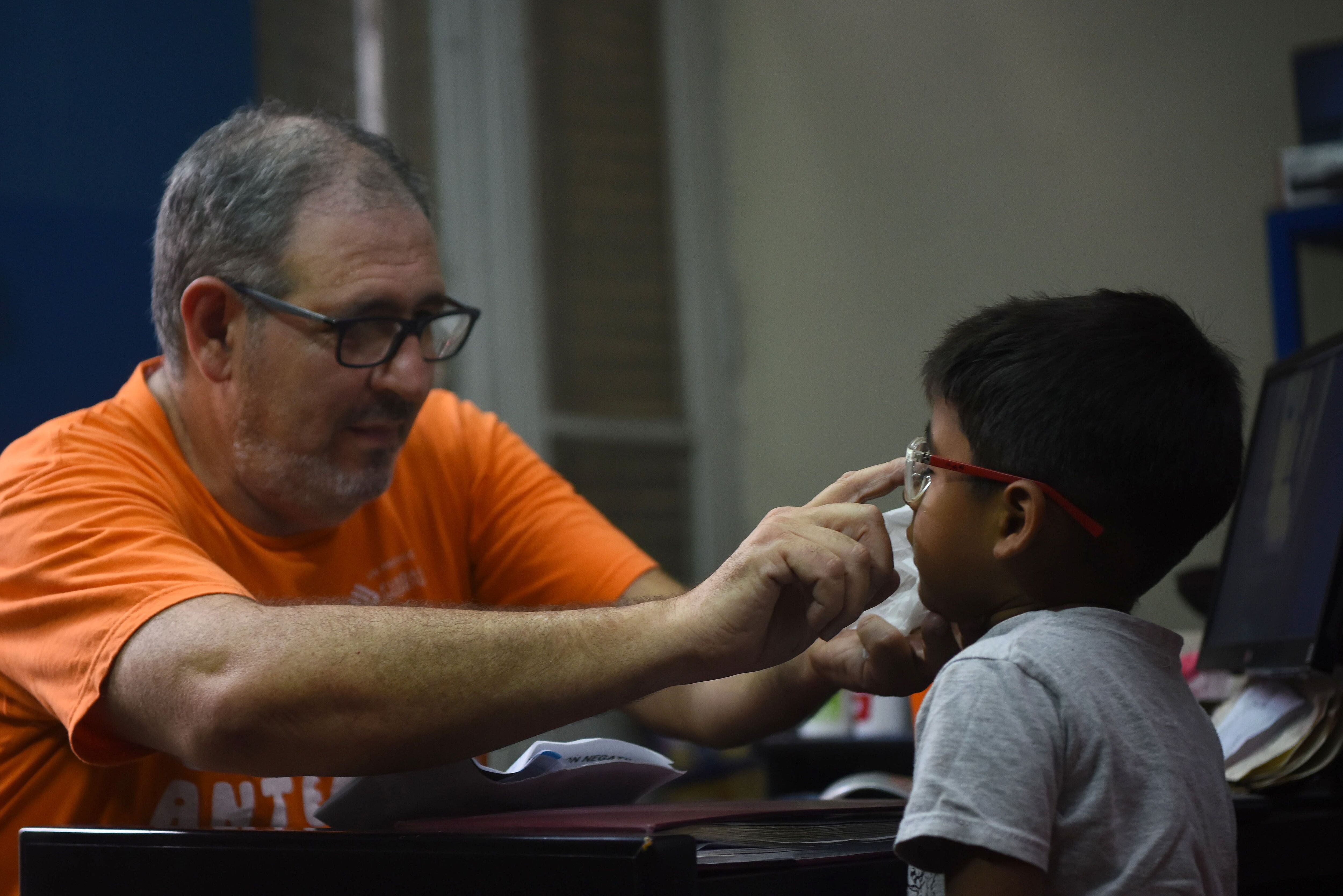 Enrique Bach, presidente de la Fundación Hacer Futuro, ayuda a un niño a elegir un par de gafas.