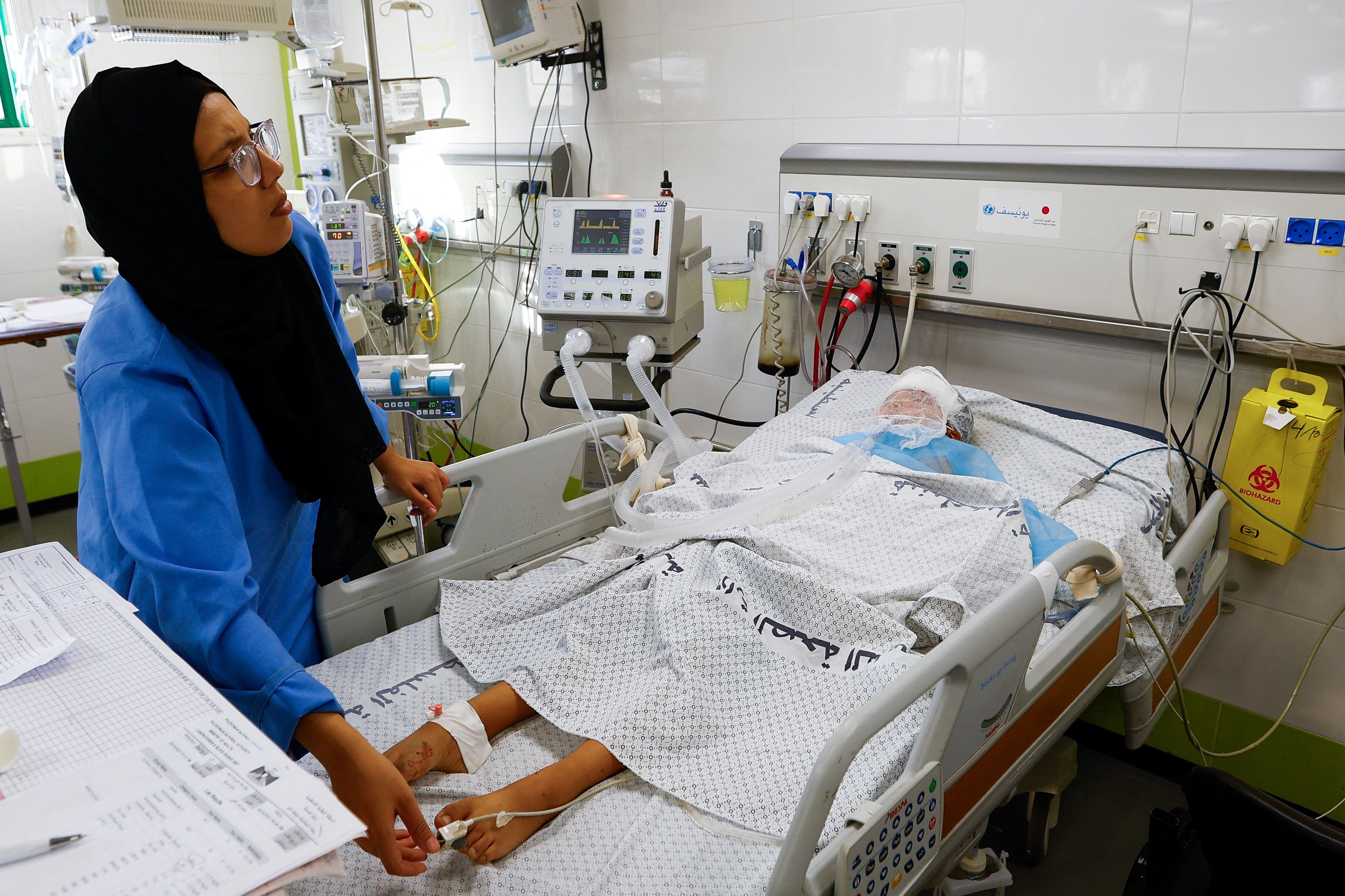 Una sanitaria atendía a un adolescente palestino ingresado en la UCI del hospital Nasser, de Gaza, el jueves. Los doctores de este centro han denunciado que solo pueden atender casos críticos debido a la escasez de combustible.