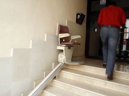 Silla mecánica para salvar las escaleras instalada en el acceso a una finca en Madrid.