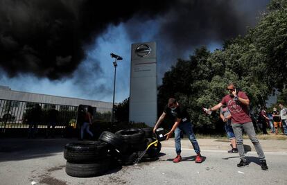 Los trabajadores de Nissan vierten combustible sobre las llantas en llamas durante una protesta frente a la sede de Barcelona.