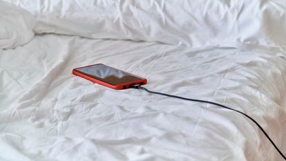 Un teléfono móvil cargando sobre una cama.