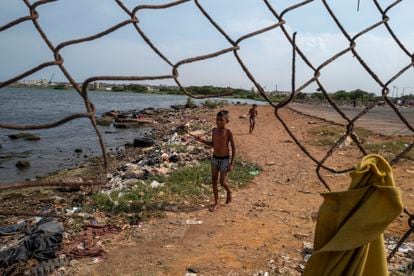 Dos niños juegan en una playa contaminada a lo largo del lago Maracaibo, cerca del mercado central de Maracaibo, el 7 de mayo de 2019.