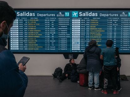 Pasajeros revisan el tablero de salidas en el Aeropuerto Internacional Benito Juárez (MEX) en la Ciudad de México, México, en 2022.