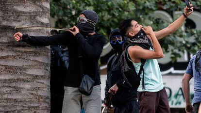 Un joven se hace un selfi mientras otro apunta un tirachinas durante una protesta en Santiago de Chile.