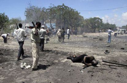 Un soldado somalí mira el cuerpo quemado de una de las víctimas del atentado en el centro de Mogadiscio.
