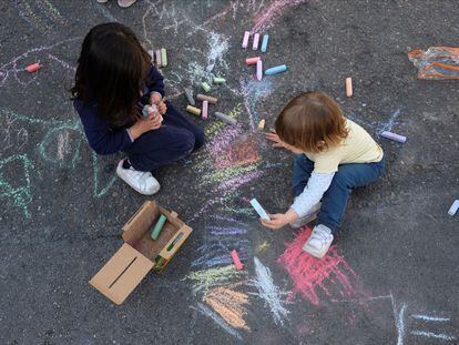 Dos menores juegan en la calle junto a un colegio de Madrid.