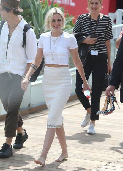 Kristen Stewart camina descalza por las calles de Cannes hacia el 'photocall' por su película 'Cafe Society'. A la derecha, alguien de la organización le lleva sus zapatos de tacón.
