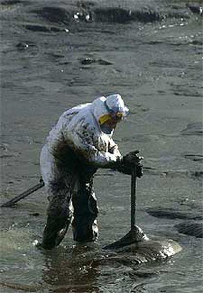 Un soldado trabaja en una densa capa de chapapote en la costa de Lira.