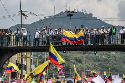 Manifestantes ondean una bandera colombiana sobre un puente peatonal en Cali.