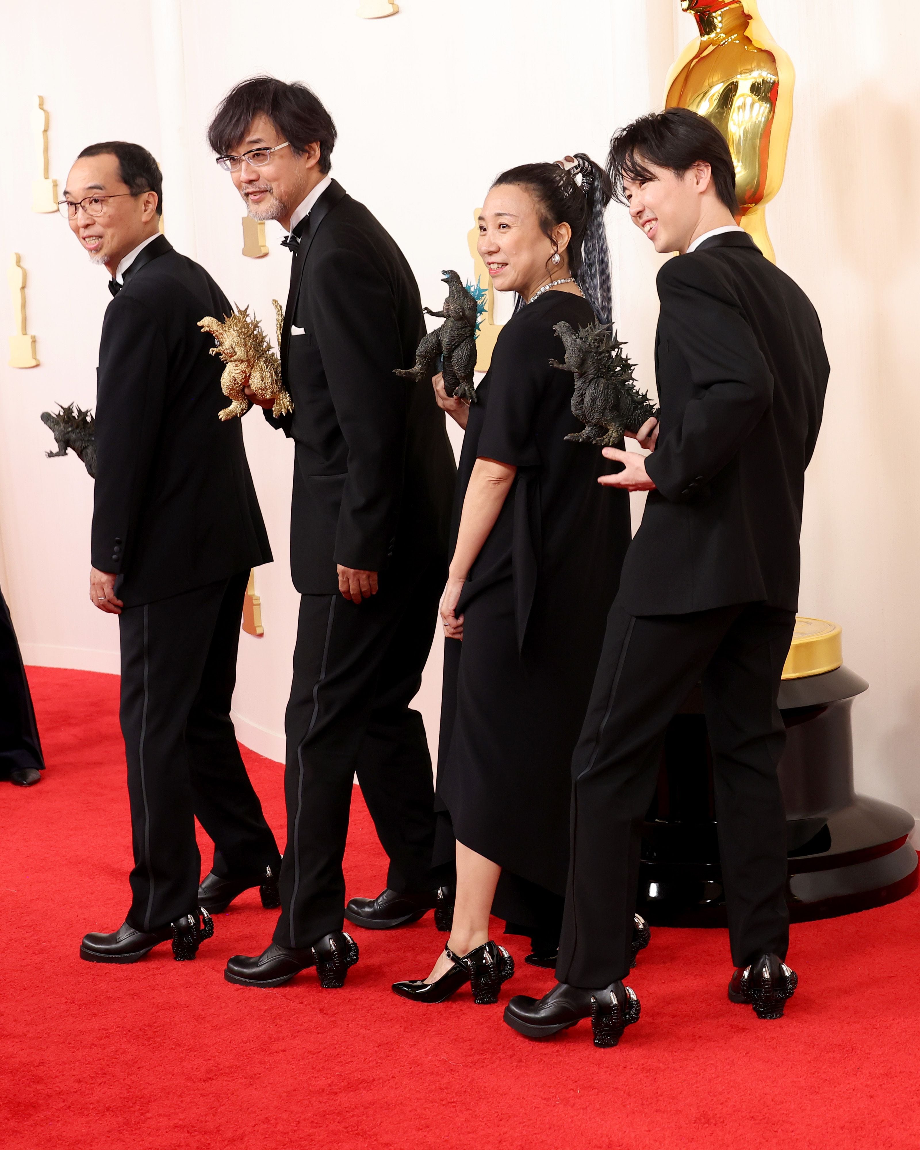 De izquierda a derecha, Masaki Takahashi, Takashi Yamazaki, Kiyoko Shibuya y Tatsuji Nojima, que representan a la película 'Godzilla: Minus One'. Yamazaki está nominado en la categoría de mejores efectos visuales por su trabajo en la cinta. Todos ellos acudieron de negro, con pequeñas figuras de Godzilla en la mano y zapatos con las garras del monstruo en el tacón.