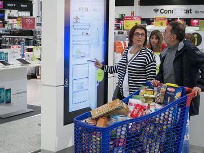 Una pareja compra electrodomesticos en la zona de nuevas tecnologias del centro comercial de Carrefour mientras hacen la compra de la semana. El Prat de Llobregat, 8 de abril de 2016 [ALBERT GARCIA]