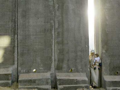 Una mujer palestina, con su hijo en brazos, pasa cerca de Jerusalén por un hueco en el muro levantado por Israel.