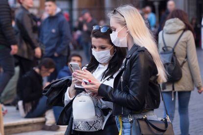 Dues dones consulten el mòbil protegides del coronavirus amb màscares, a la Piazza della Rotonda, a Roma.