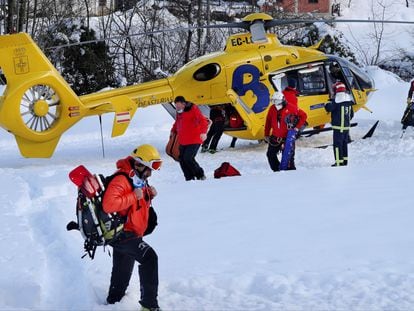 Rescatistas del Servicio de Emergencias de Asturias junto al helicóptero medicalizado de Bomberos de Asturias, que ha sobrevolado este miércoles la zona del alud.