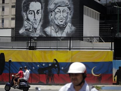 Una moto pasa frente a un mural de Simón Bolívar y Hugo Chávez en Caracas, en una imagen de 2022.