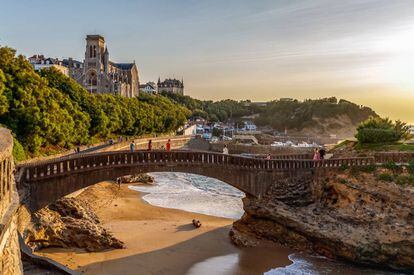 El puente de piedra de Rocher du Basta, en Biarritz, y, al fondo, la iglesia de Sainte Eugénie de la localidad francesa.