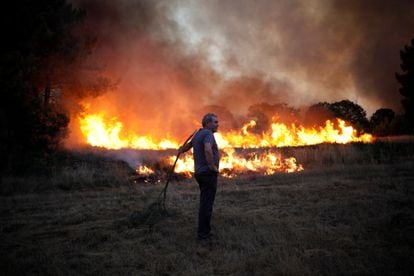 Un hombre mira como el fuego quema el pasto en Verín. 