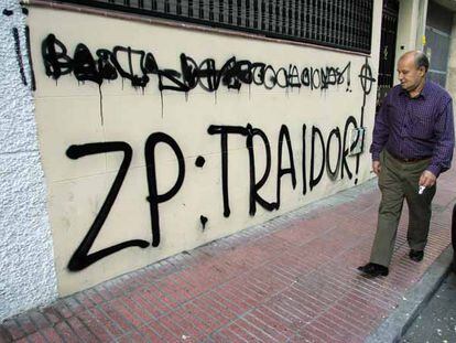 Un viandante observa las pintadas efectuadas en la fachada de la sede del PSOE en Getafe.