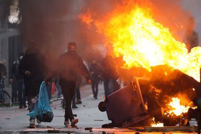 Un manifestante pasa cerca de un contenedor en llamas, este domingo en Bruselas.