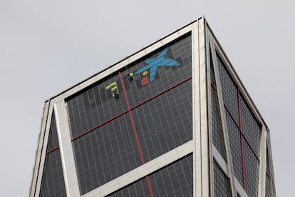Varios operarios quitan el logotipo de Bankia para incorporar, sobre las ventanas más altas del edificio de Torre Europa de Madrid, la imagen de CaixaBank.