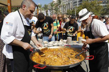 Dos cocineros emplatan una paella de marisco en la plaza del Ayuntamiento de Valencia.