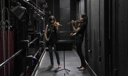 Dos chicas ensayan cn sus violines entre bambalinas, en el Teatro del Canal.