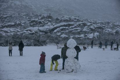 Varias personas hacen un muñeco de nieve, este viernes en La Pedriza (norte de Madrid).